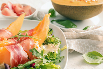 Delicious melon with prosciutto and herbs on plate