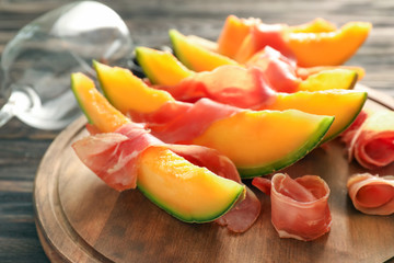 Delicious melon with prosciutto on wooden board