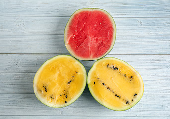 Halves of yellow and red watermelons on white wooden table