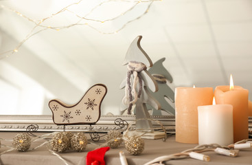 Burning candles with garland on mantelpiece decorated for Christmas