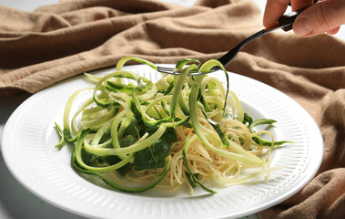 Eating of tasty spaghetti with zucchini, closeup
