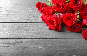 Beautiful bouquet of red roses on wooden background