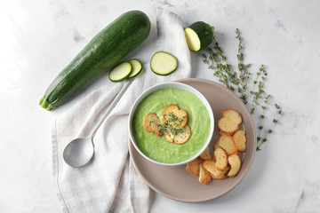 Tasty zucchini soup with croutons in bowl on light table