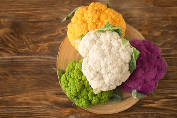 Plate with different cauliflower cabbage on wooden table