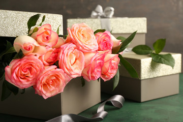 Box with beautiful roses and gifts on color table