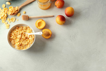 Bowl with healthy cornflakes, milk, honey and peaches on light table