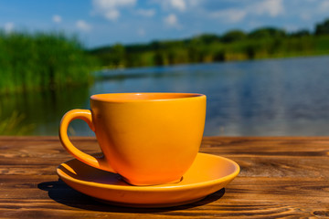Cup of coffee on wooden table at the riverside