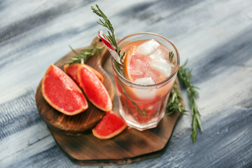 Fresh grapefruit cocktail with rosemary in glass on wooden board