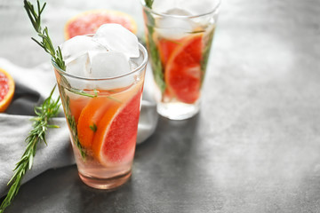 Fototapeta na wymiar Fresh grapefruit cocktail with rosemary in glass on grey table