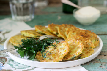 Pancakes with zucchini and sweet corn, served with sour cream, parsley and dill. Vegetarian food.