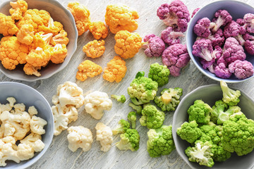 Bowls with colorful cauliflowers on light table