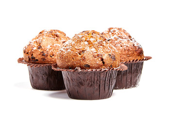 Three muffins with chips of chocolate and powdered sugar, isolated on white background. Selective focus