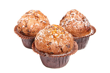 Three muffins with chips of chocolate and powdered sugar, isolated on white background. Selective focus