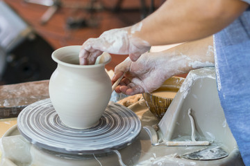the Potter molds a pot from clay on a Potter's wheel. The master's hands make a pot on the potter's...