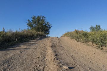 Country road and blue sky. Hill. Steppe. The road in rural areas