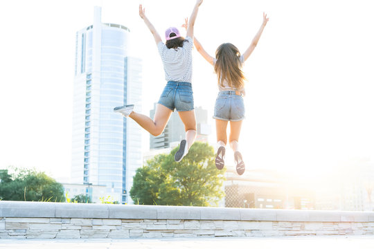Two young happy hipster girls having fun, smiling, laughing, jumping, walking outdoor on the street, summer relax concept