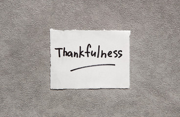 Thankfulness - word on real paper with gray background