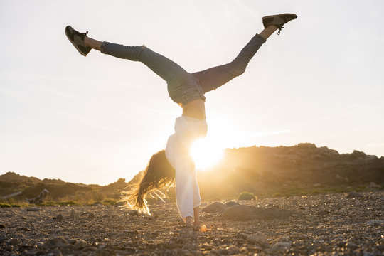 Young woman at the beach, doing handstand at sunset