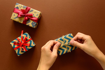 Woman's hands decorate present box on paper background. New Year, holidays and celebration decorations concept. Copy space. Flat lay