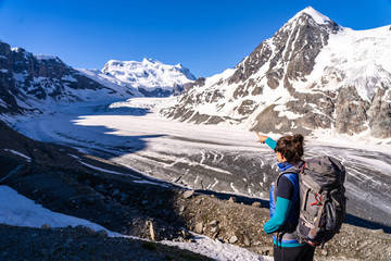 Young female hiker looking at Glacier de Corbassiere. Hiking a mountain trail around Glacier and Grand Combin in Valais Alps (Pennine Alps), Switzerland.