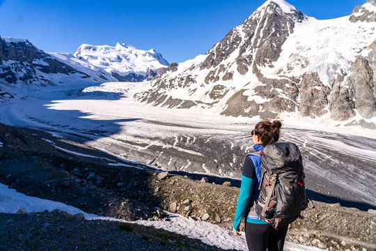 Young female hiker looking at Glacier de Corbassiere. Hiking a mountain trail around Glacier and Grand Combin in Valais Alps (Pennine Alps), Switzerland.