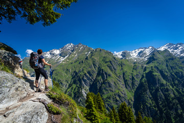 Fototapeta premium Female traveler with backpack hiking mountain trail and admiring views of Swiss Alps in Val de Bagnes area, Switzerland.