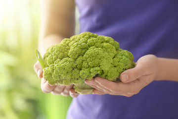 Woman holding green cauliflower on blurred background, closeup