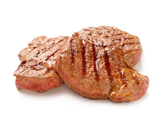 Tasty grilled steaks on white background