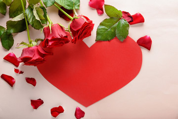 Beautiful red roses and paper heart on light background