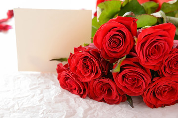 Beautiful red roses and card on packing paper, closeup