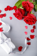 Beautiful red roses and gift box on light background