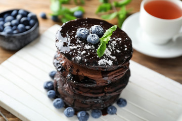 Tasty chocolate pancakes with blueberries on white board