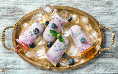 Metal tray with tasty blueberry popsicles on light wooden table
