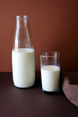 Milk bottle and milk glass on brown paper background. Healthy eating concept