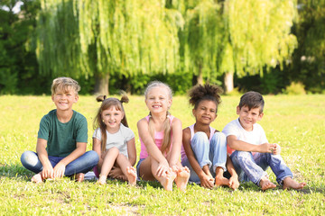 Fototapeta premium Cute little children sitting on grass outdoors