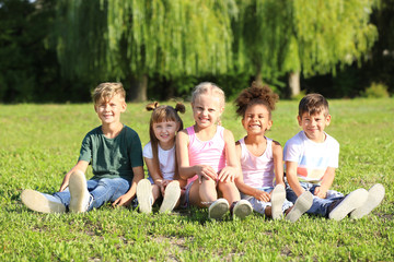 Cute little children sitting on green grass outdoors