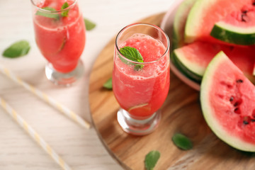 Glass with fresh smoothie and watermelon slices on wooden board