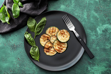 Plate with tasty grilled zucchini on green table