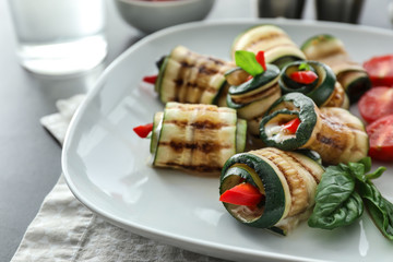 Plate with tasty zucchini rolls on table, closeup
