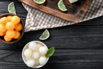 Bowls with delicious melon balls on wooden table