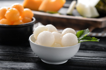 Bowl with delicious melon balls on wooden table