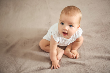 Adorable baby sitting on bed at home