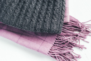Gray woolen knitted hat and pink scarf on a white background