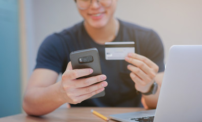 close up teenager man hand holding smartphone and trying to paying by credit card:shopping online concept.