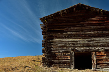 Eine wettergegerbte Holzhütte vor blauem Himmel