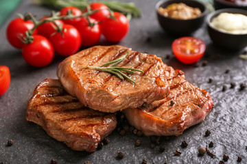 Tasty grilled steaks with spices on slate plate
