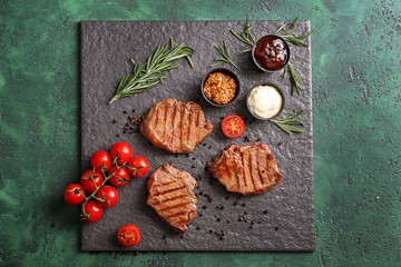 Tasty grilled steaks with different sauces on slate plate