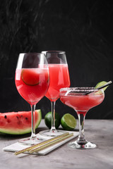 Glasses with fresh watermelon smoothie on grey table against dark background