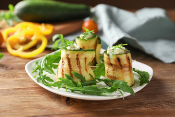 Tasty zucchini rolls with cheese and arugula on plate