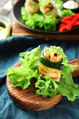 Tasty zucchini roll with prosciutto on wooden board